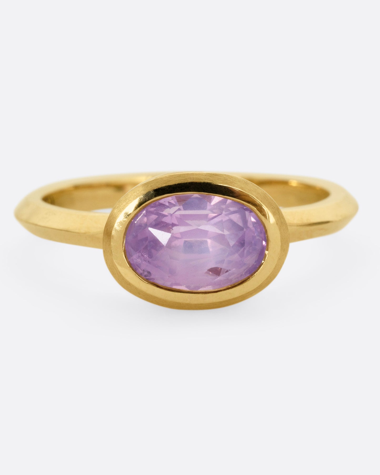 A yellow gold ring with a lilac sapphire, shown from the front.