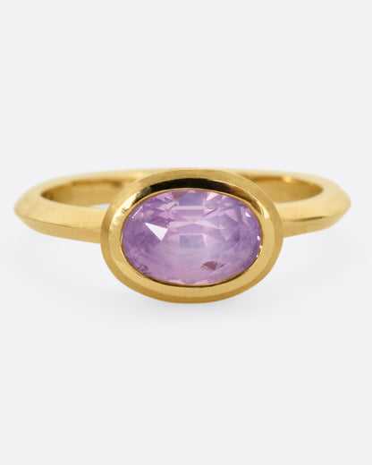 A yellow gold ring with a lilac sapphire, shown from the front.
