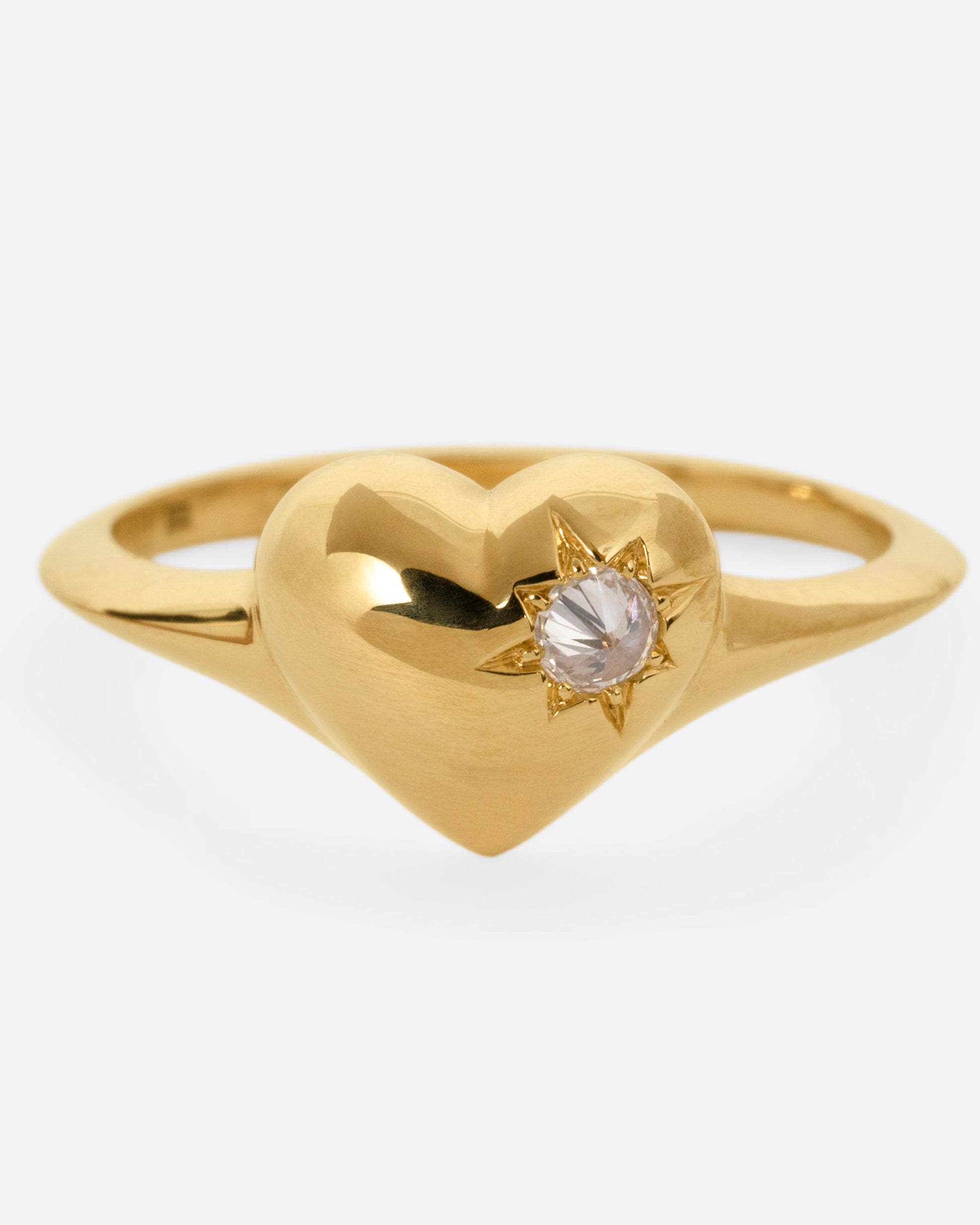 A yellow gold heart shaped ring with a reverse set diamond, shown from the front.