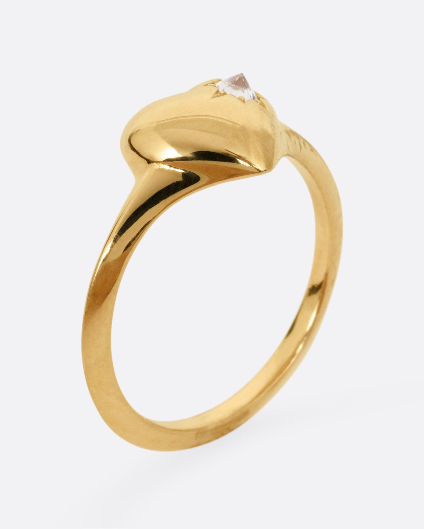 A yellow gold heart shaped ring with a reverse set diamond, shown from the side standing up.