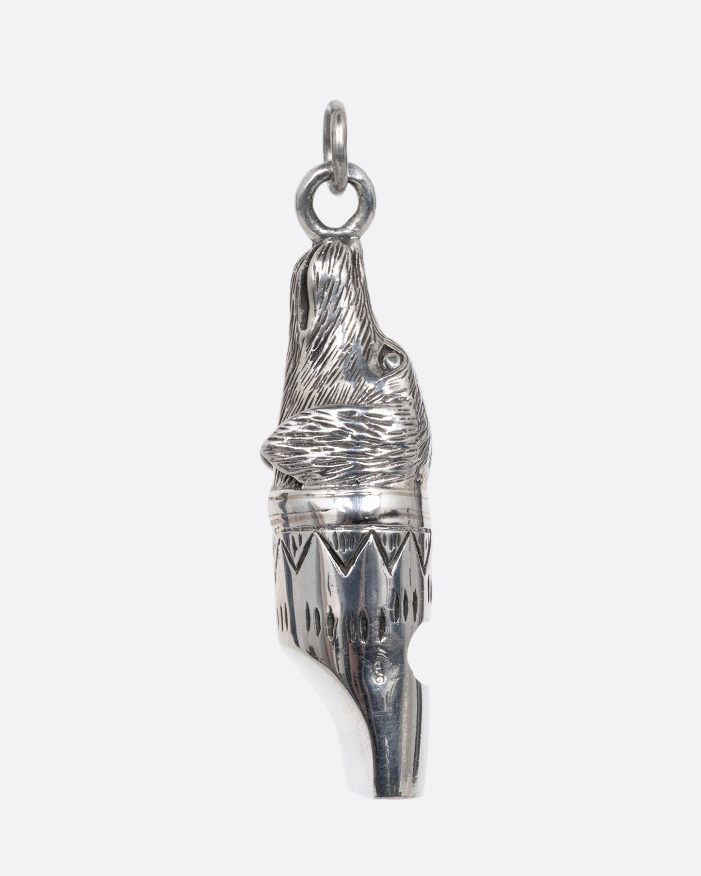 A silver dog whistle with a dog head at one end. Shown from the side.