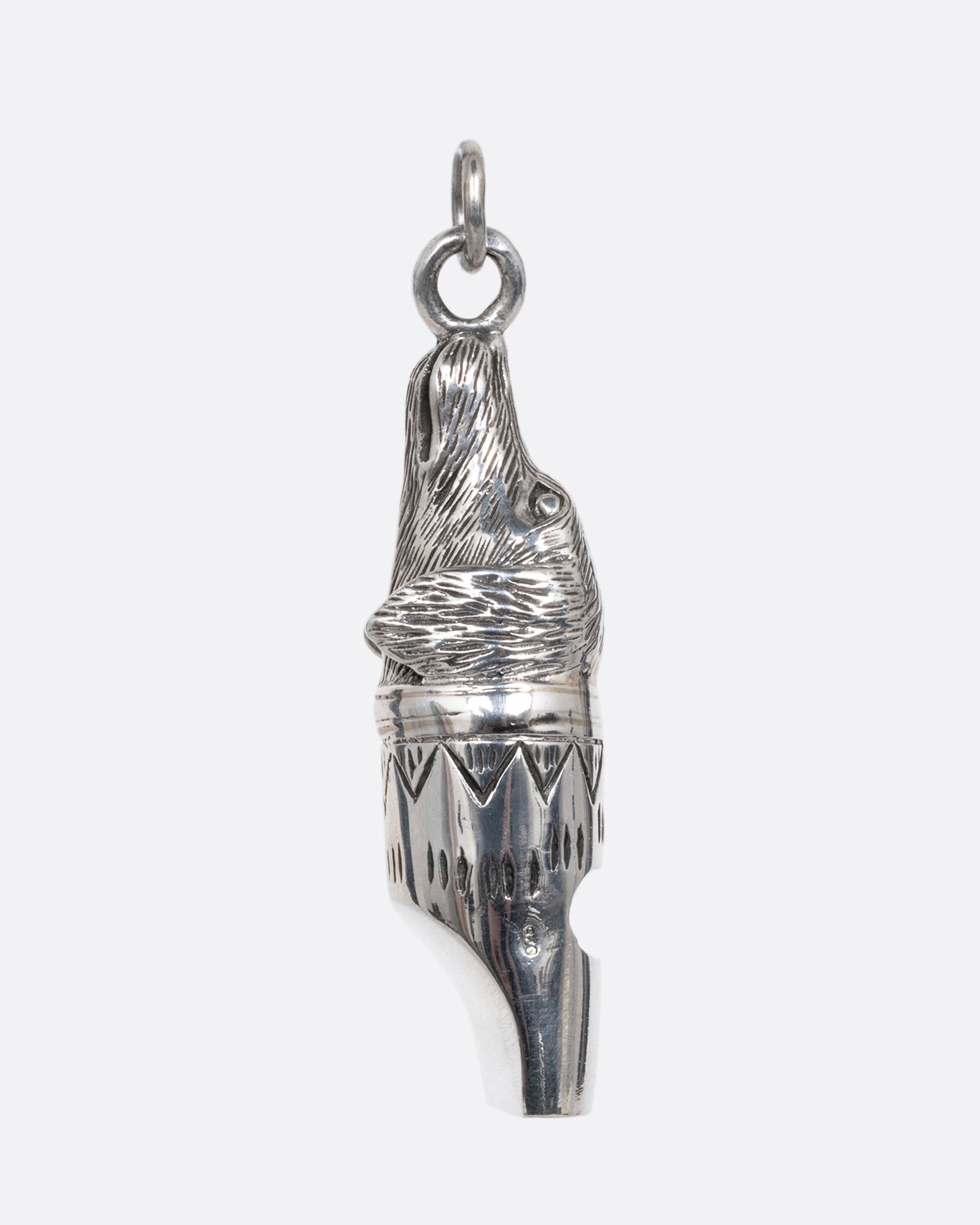 A silver dog whistle with a dog head at one end. Shown from the side.