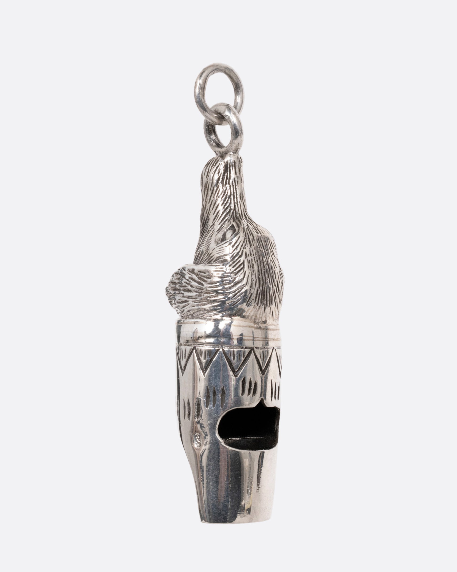 A silver dog whistle with a dog head at one end. Shown from the side.