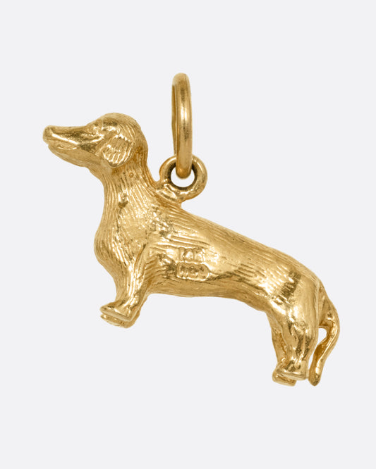 A yellow gold miniature dachshund pendant, shown from the front.