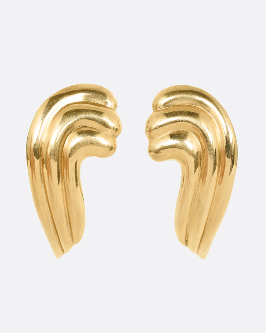 A pair of wavy yellow gold stud earrings, shown from the front.