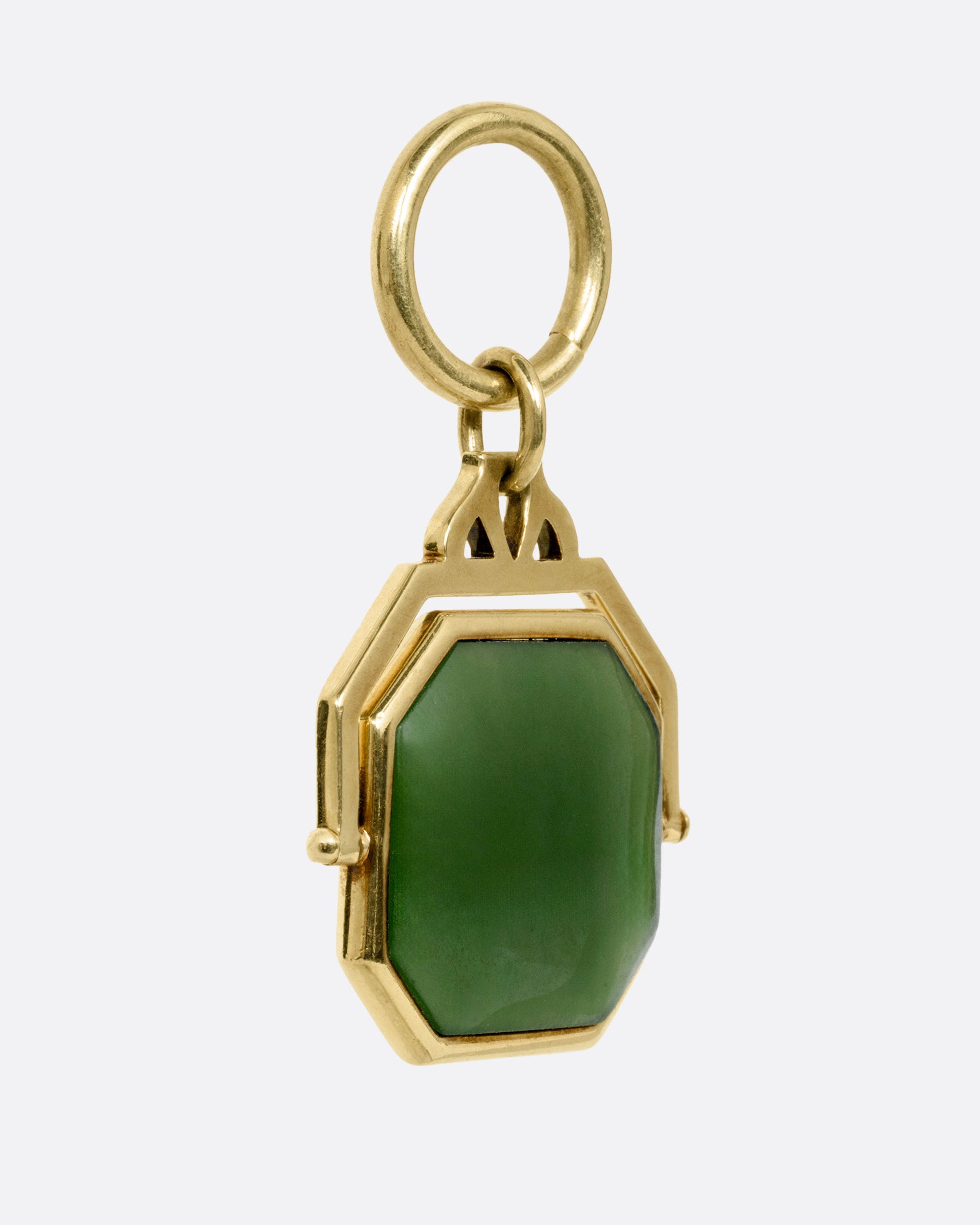 A yellow gold pendant with a spinning swath of jade, shown from the front.