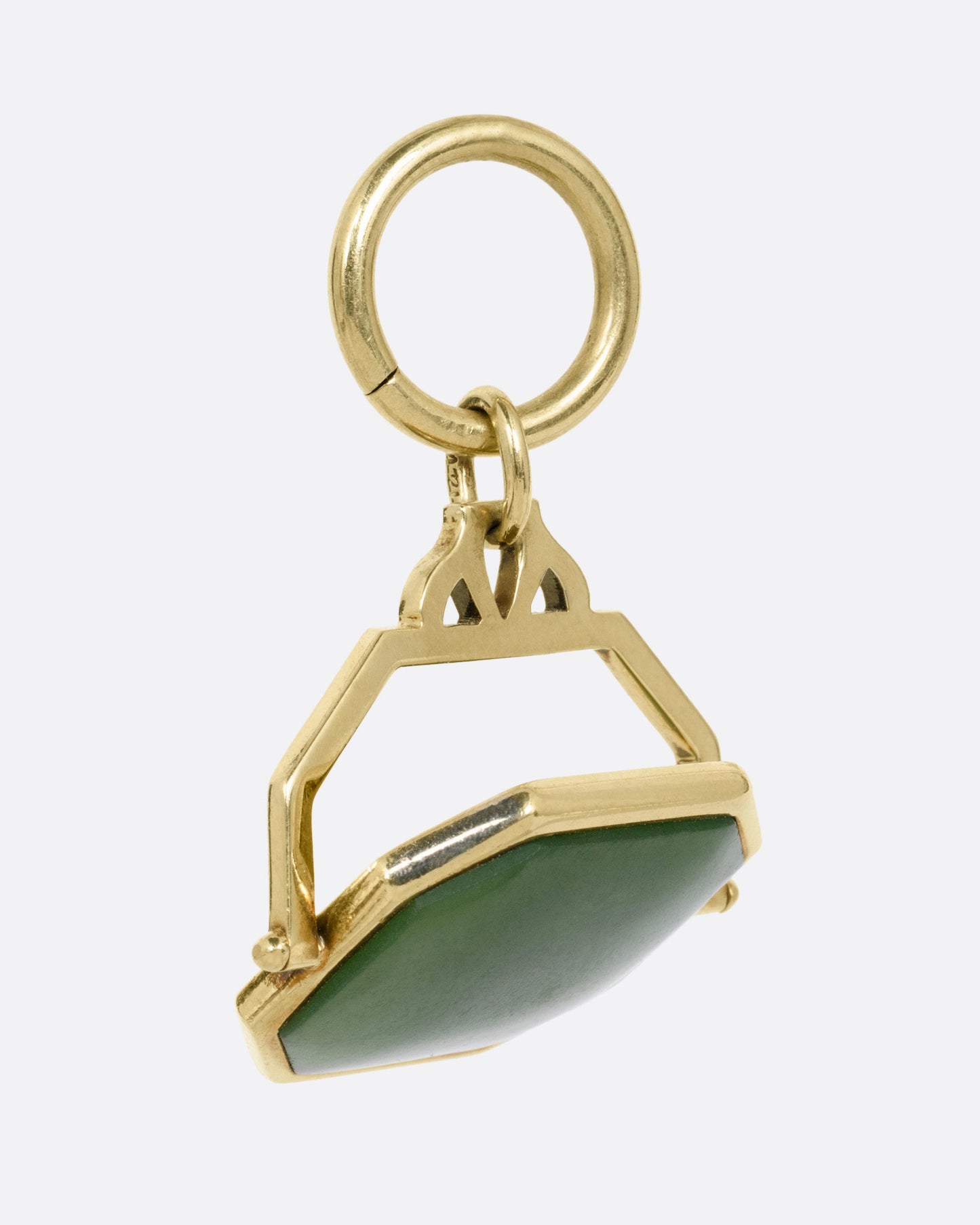 A yellow gold pendant with a spinning swath of jade, shown from the side.