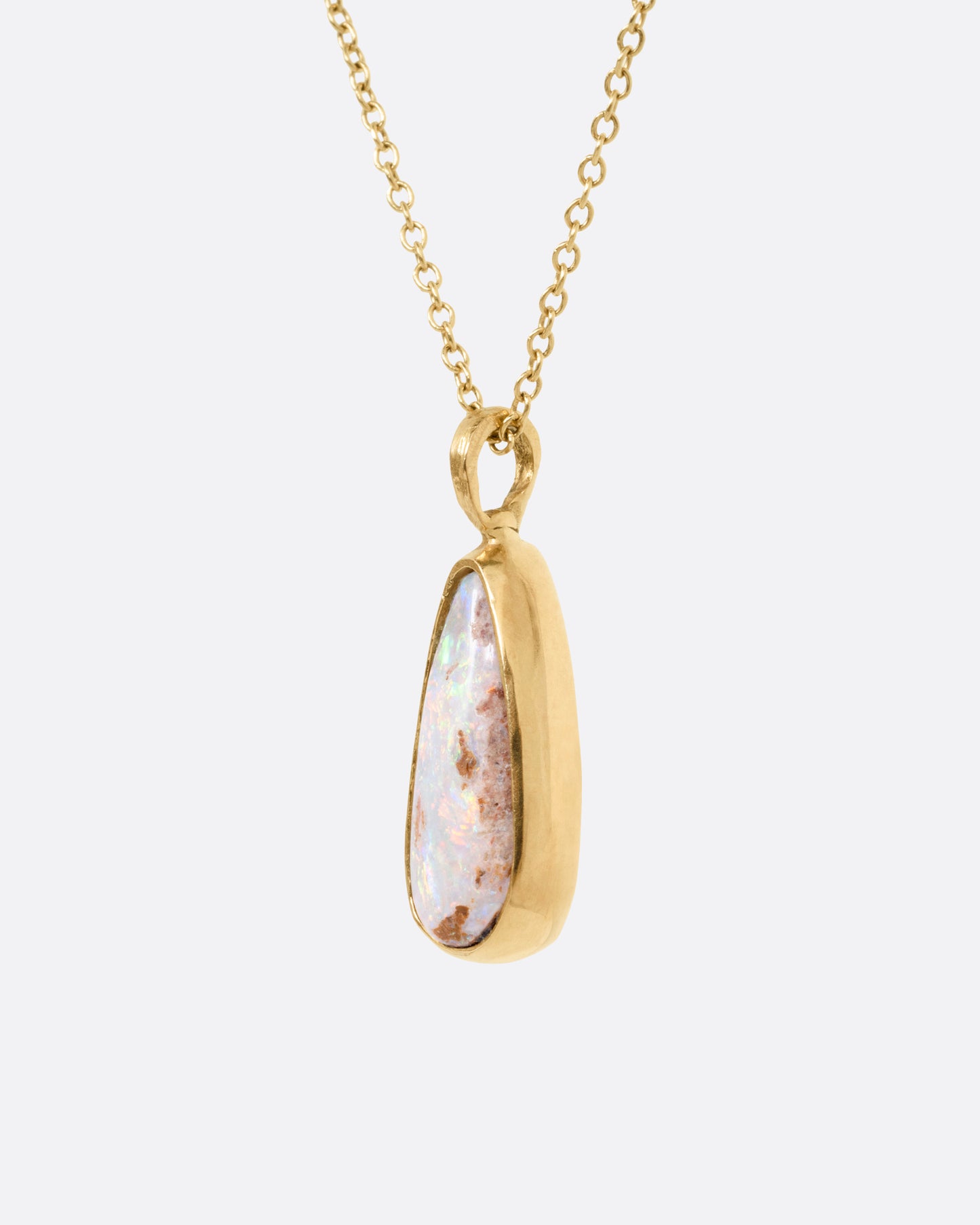 A yellow gold cable chain necklace with a teardrop shaped Australian opal pendant. Shown from the side.