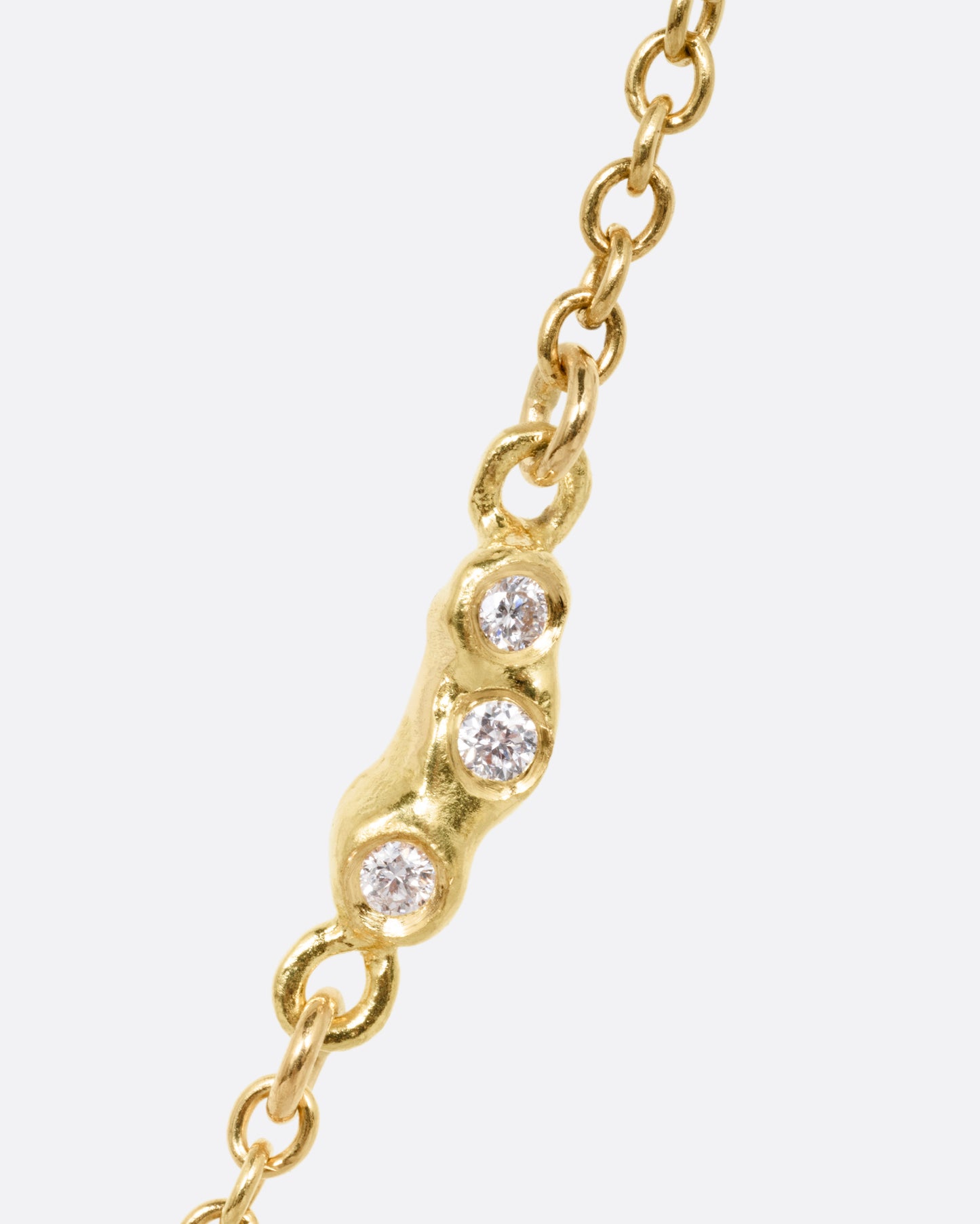 A close up of diamond detailing on a yellow gold cable chain necklace.