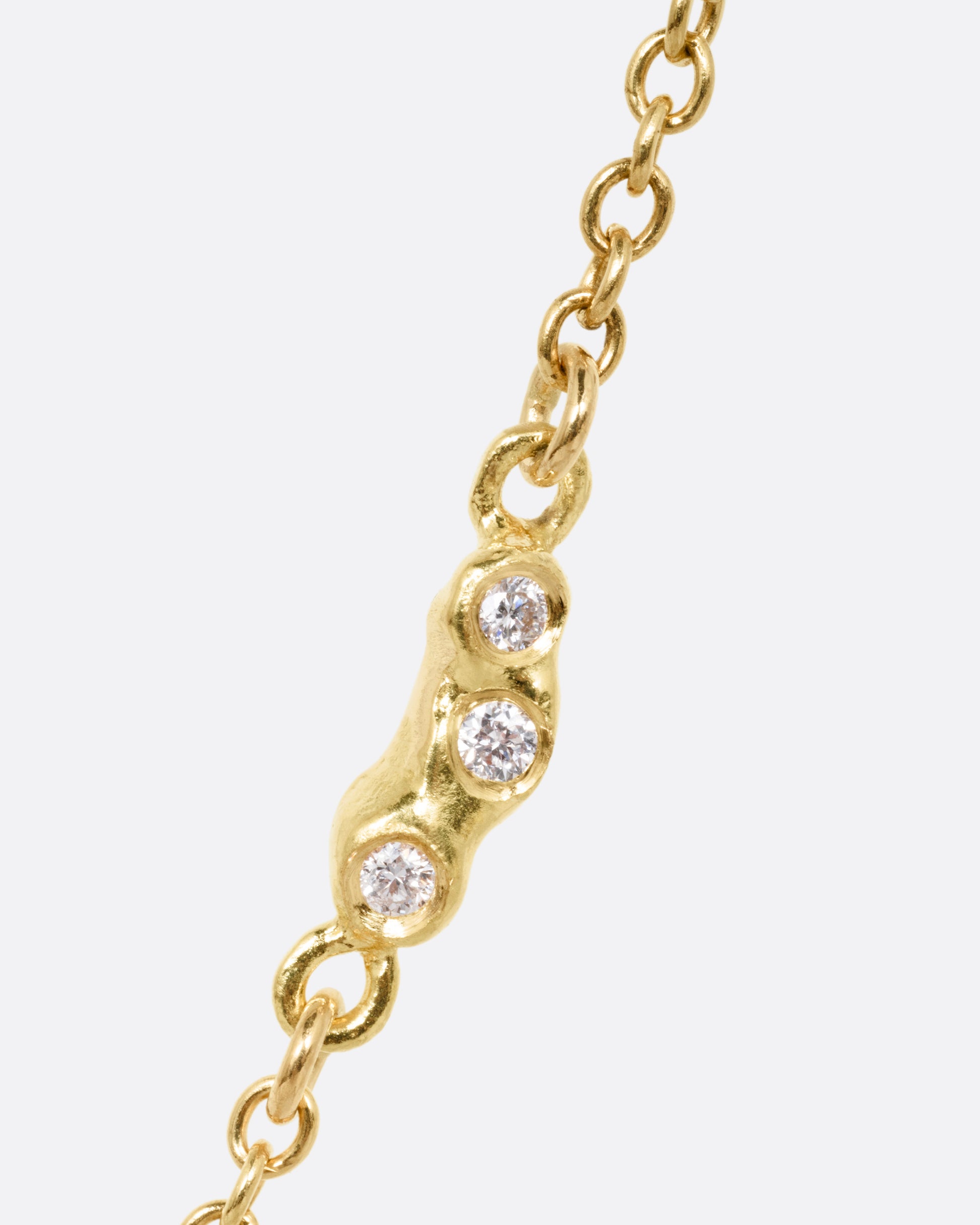 A close up of diamond detailing on a yellow gold cable chain necklace.