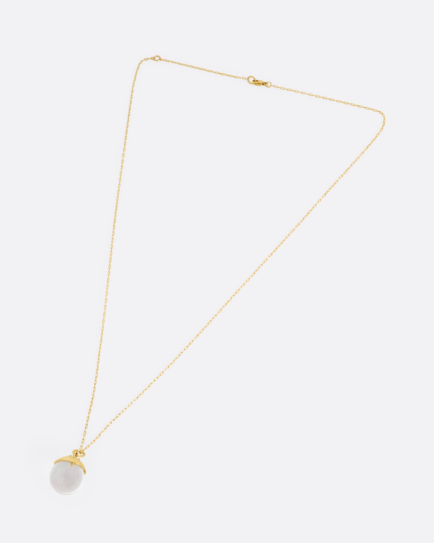 A yellow gold cable chain necklace with a quartz sphere pendant topped with gold and reverse set diamonds. Shown from the front.