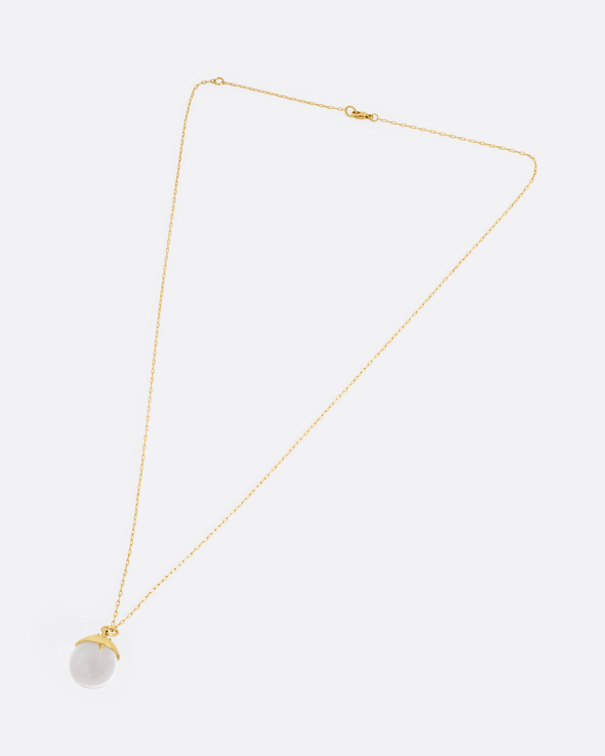A yellow gold cable chain necklace with a quartz sphere pendant topped with gold and reverse set diamonds. Shown from the front.