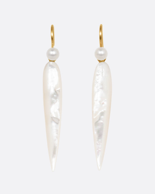 A pair of pointed mother of pearl drop earrings with yellow gold ear hooks, shown from the front.