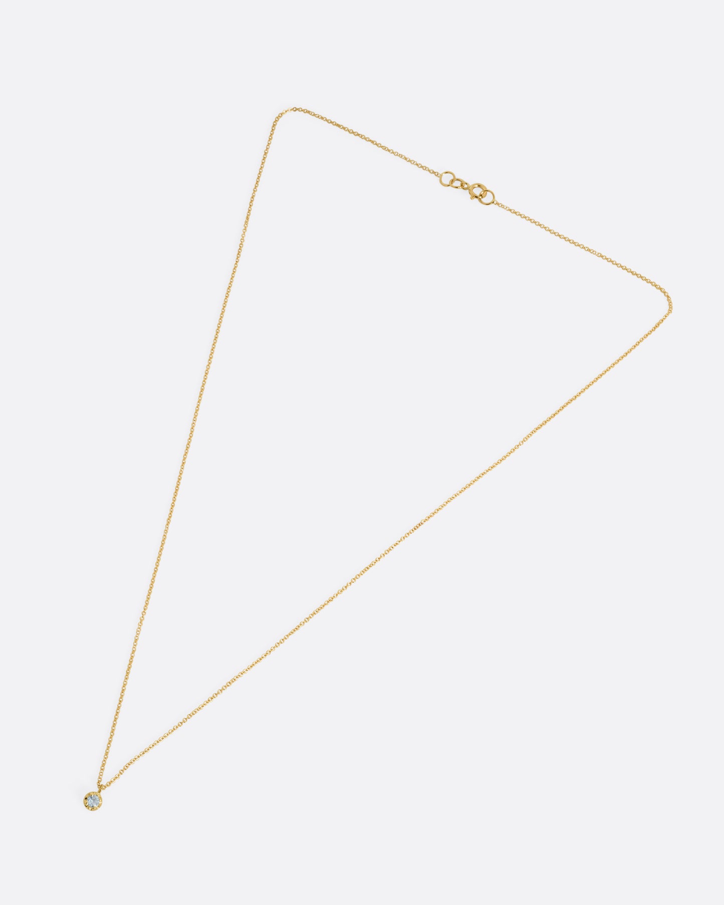 A yellow gold cable chain necklace with a  prong set aquamarine, shown from the front.