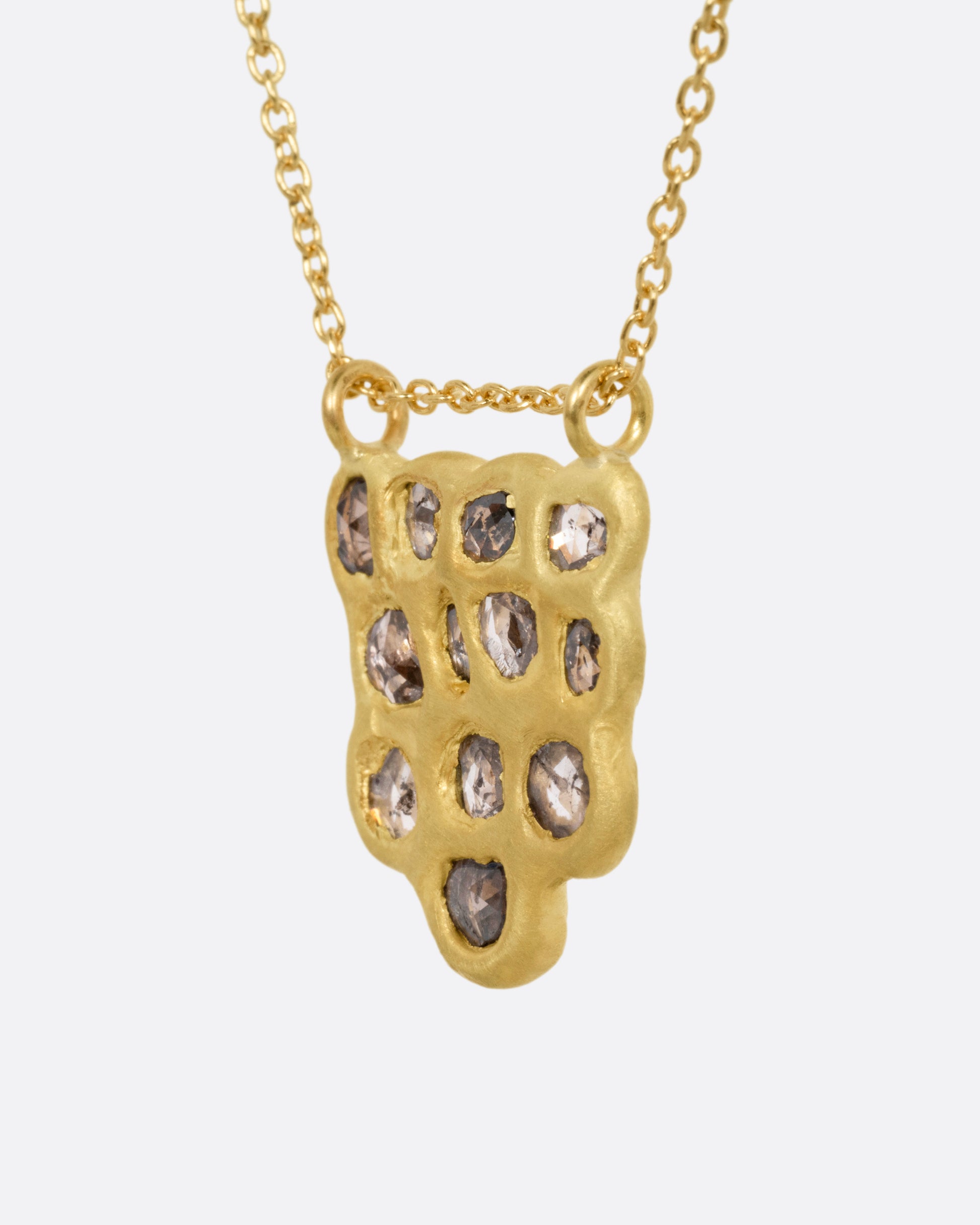 A yellow gold pendant necklace with a cluster of rose cut diamonds, shown from the side.