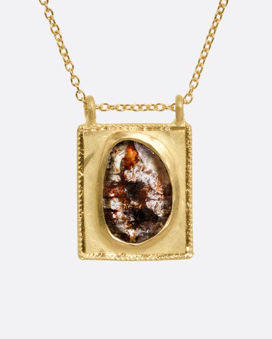 A yellow gold pendant necklace with a rose cut salt and pepper diamond in a rectangular gold frame, with a double bail. Shown from the front.