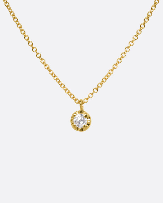 A yellow gold cable chain necklace with a  prong set white diamond, shown from the front.