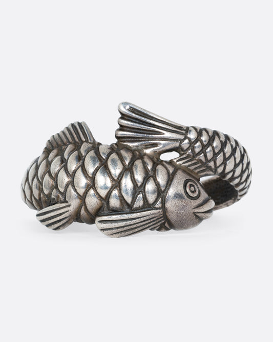 A silver fish shaped bracelet shown from the front.