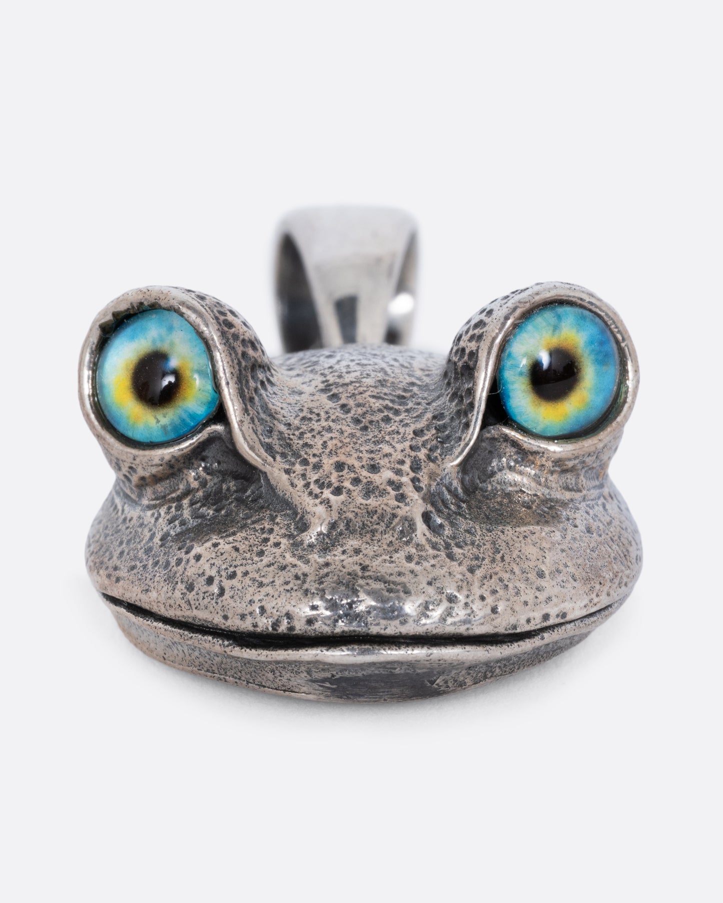 A silver frog head pendant with blue and yellow eyes, shown from the bottom.