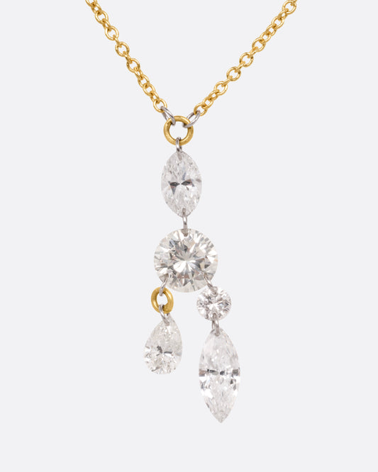A yellow gold cable chain necklace with an arrangement of free set round, marquise, and pear shaped diamonds in platinum jump rings, shown from the front.