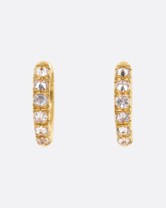 A pair of yellow gold hoop earrings with reverse set diamonds. Shown from the front.
