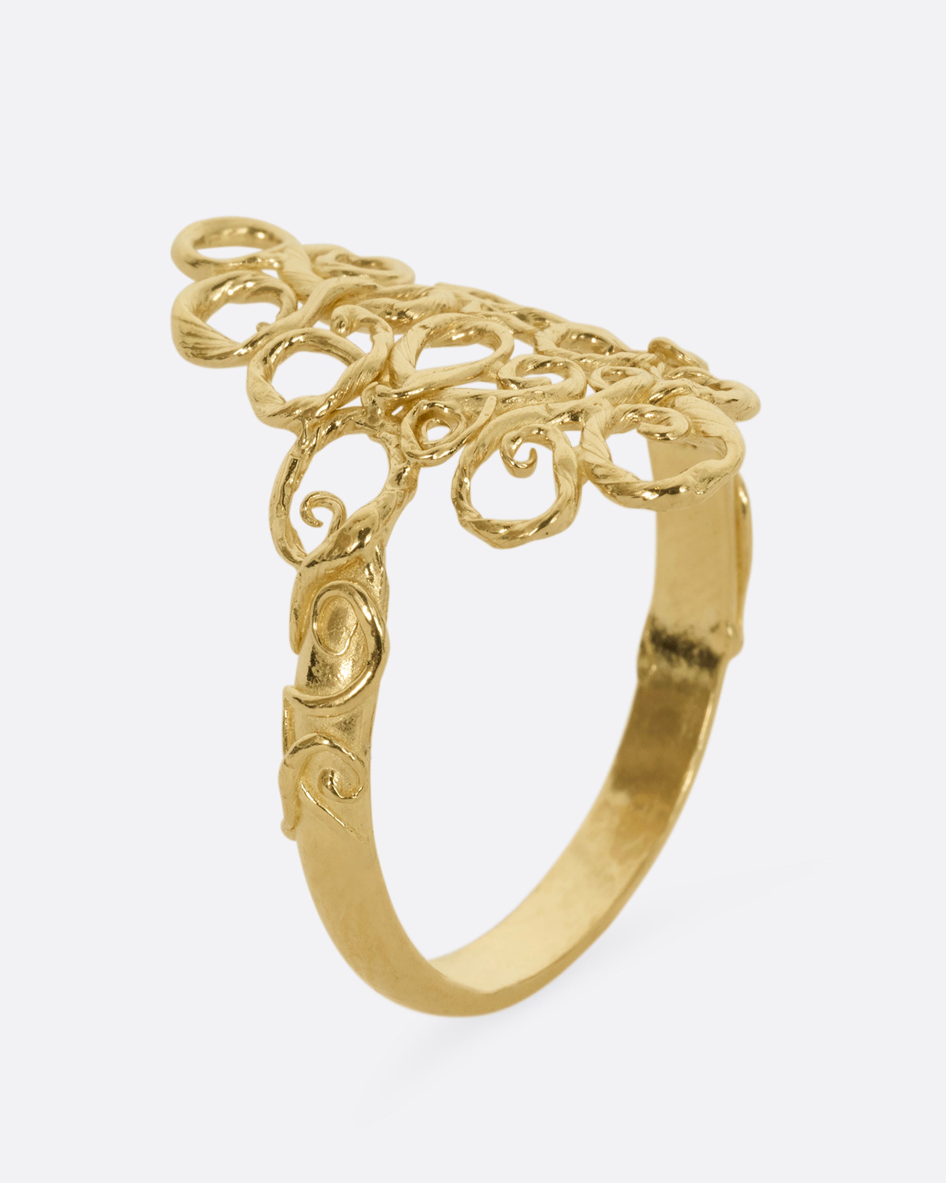 A yellow gold ring with filigree in the shape of a diamond at its center. Shown from the side.