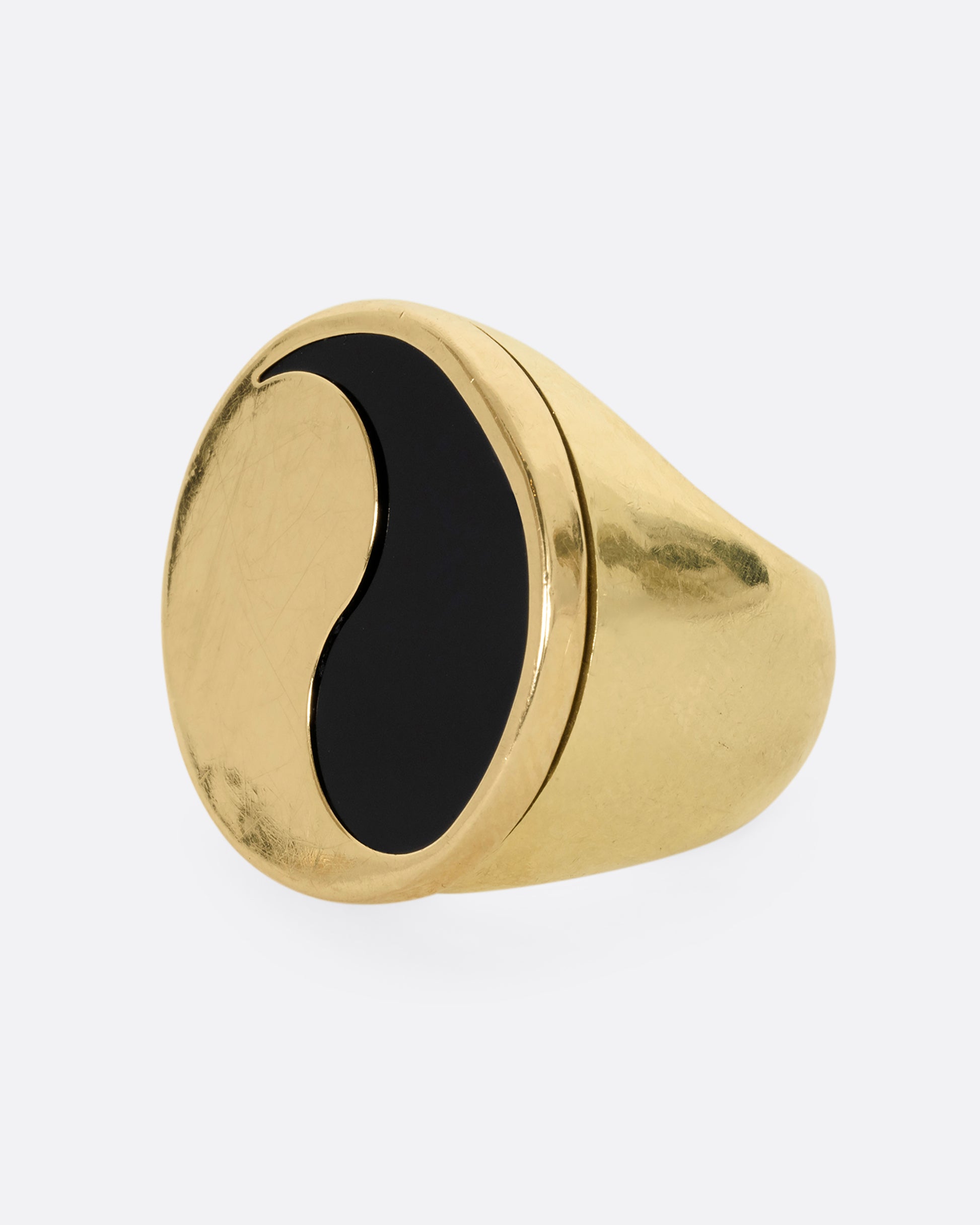 A yellow gold ring with a yin yang symbol made of onyx. Shown from the side.