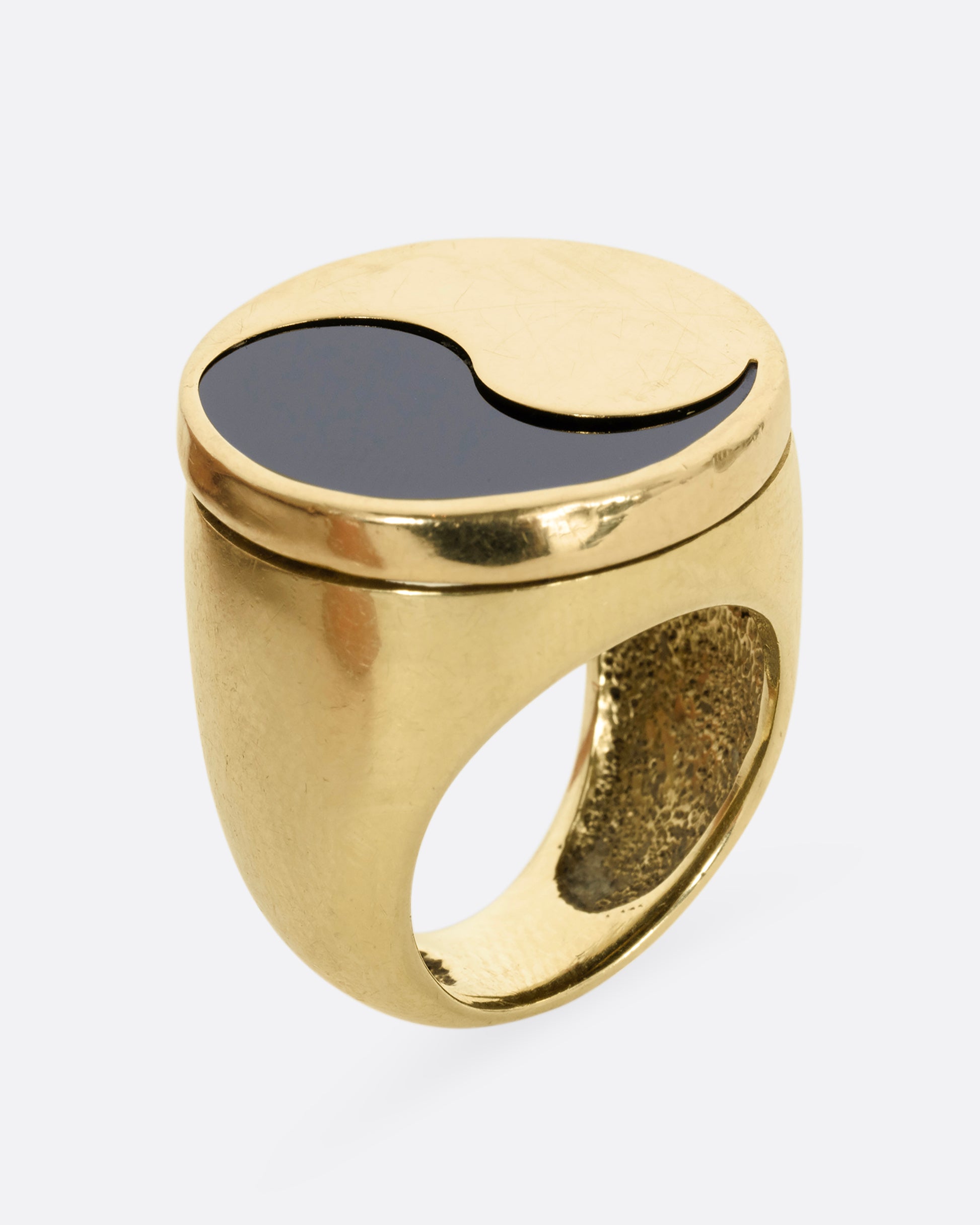 A yellow gold ring with a yin yang symbol made of onyx. Shown from the side, standing up.