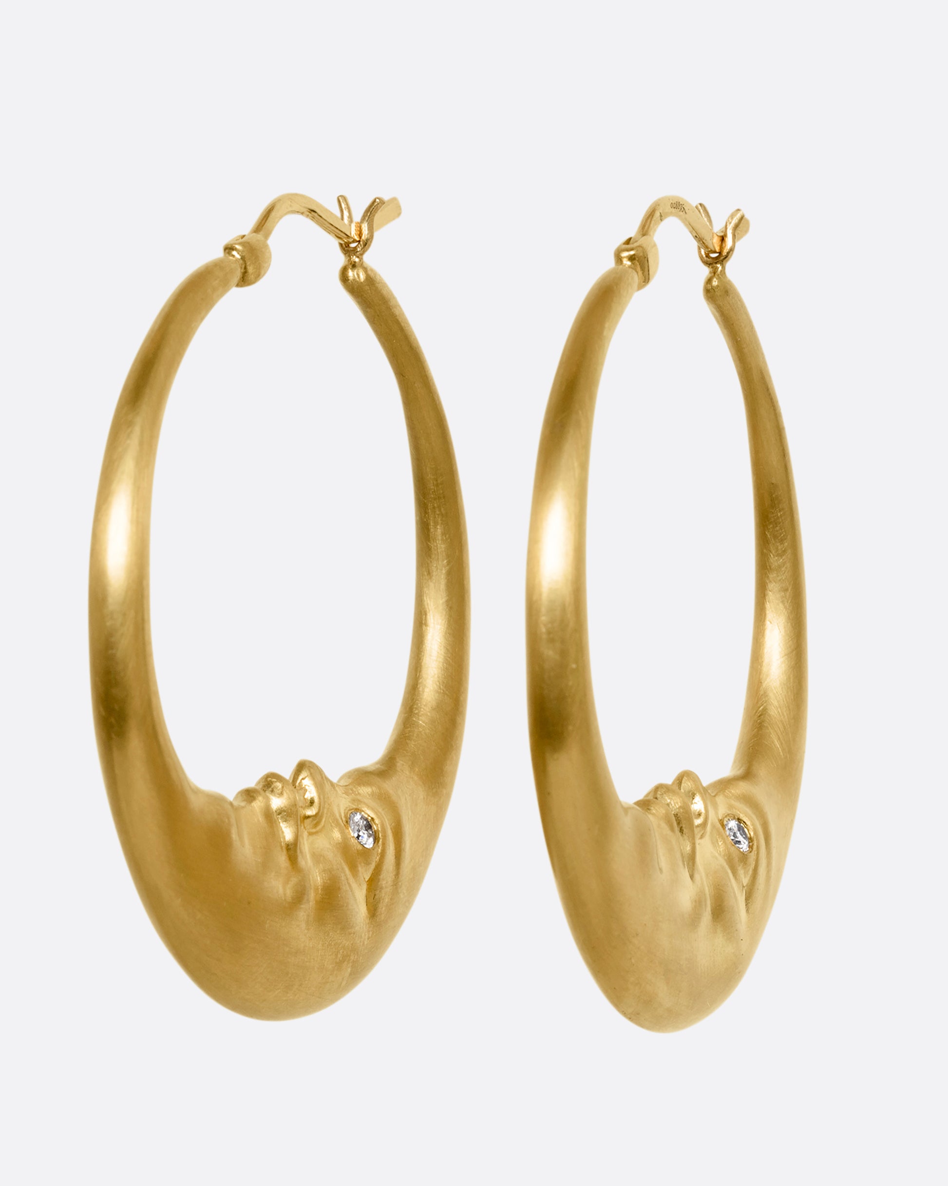 yellow gold crescent shaped oop earring with diamond eyes shown from the side