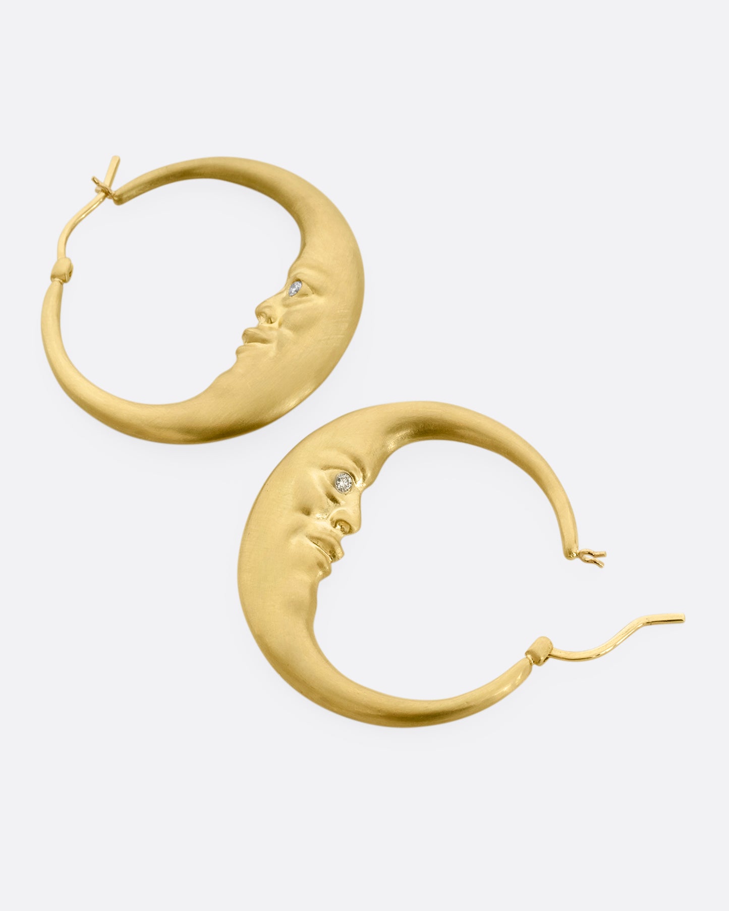 yellow gold crescent shaped oop earring with diamond eyes shown lying flat