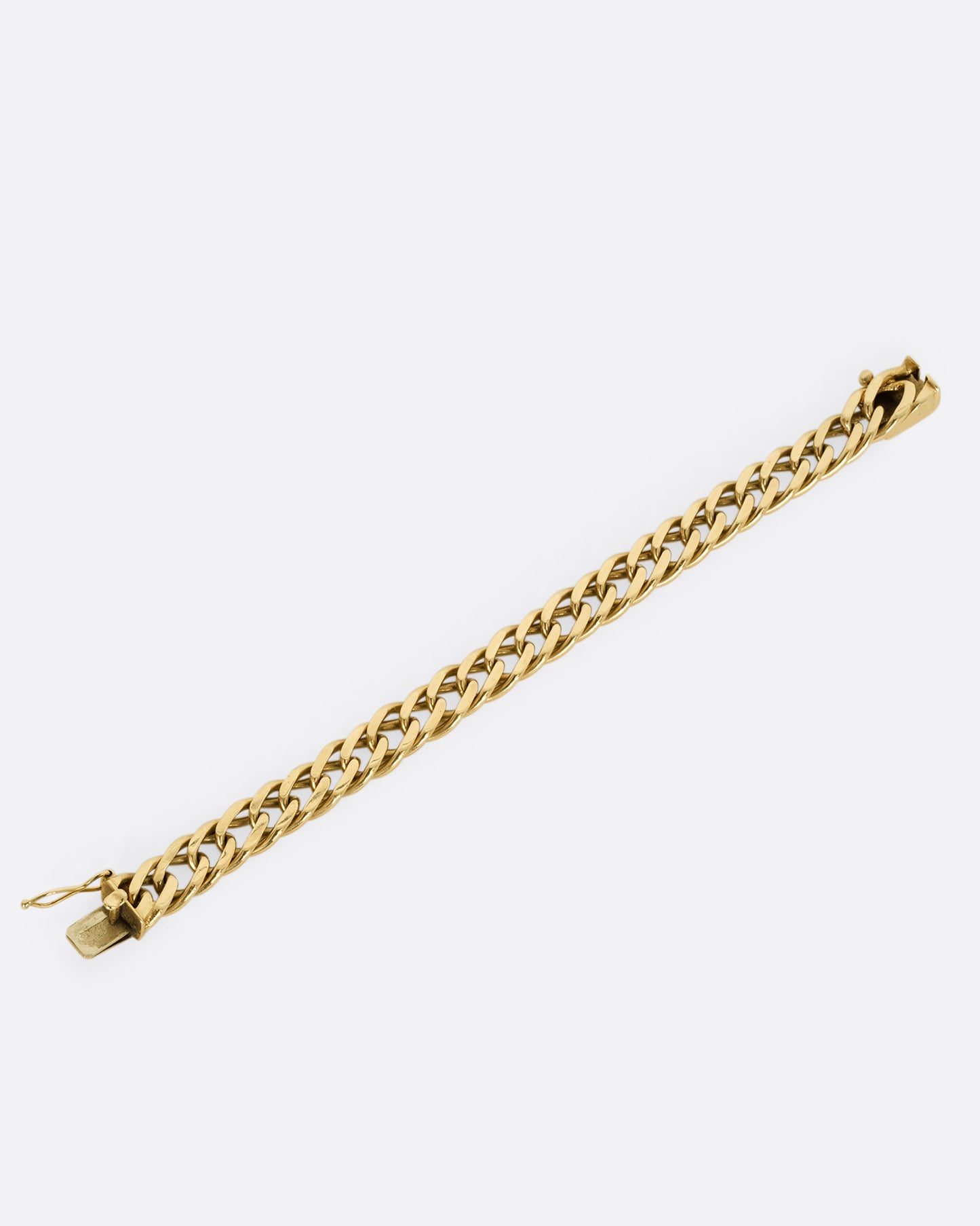 A yellow gold double curb chain bracelet. Shown laying flat.
