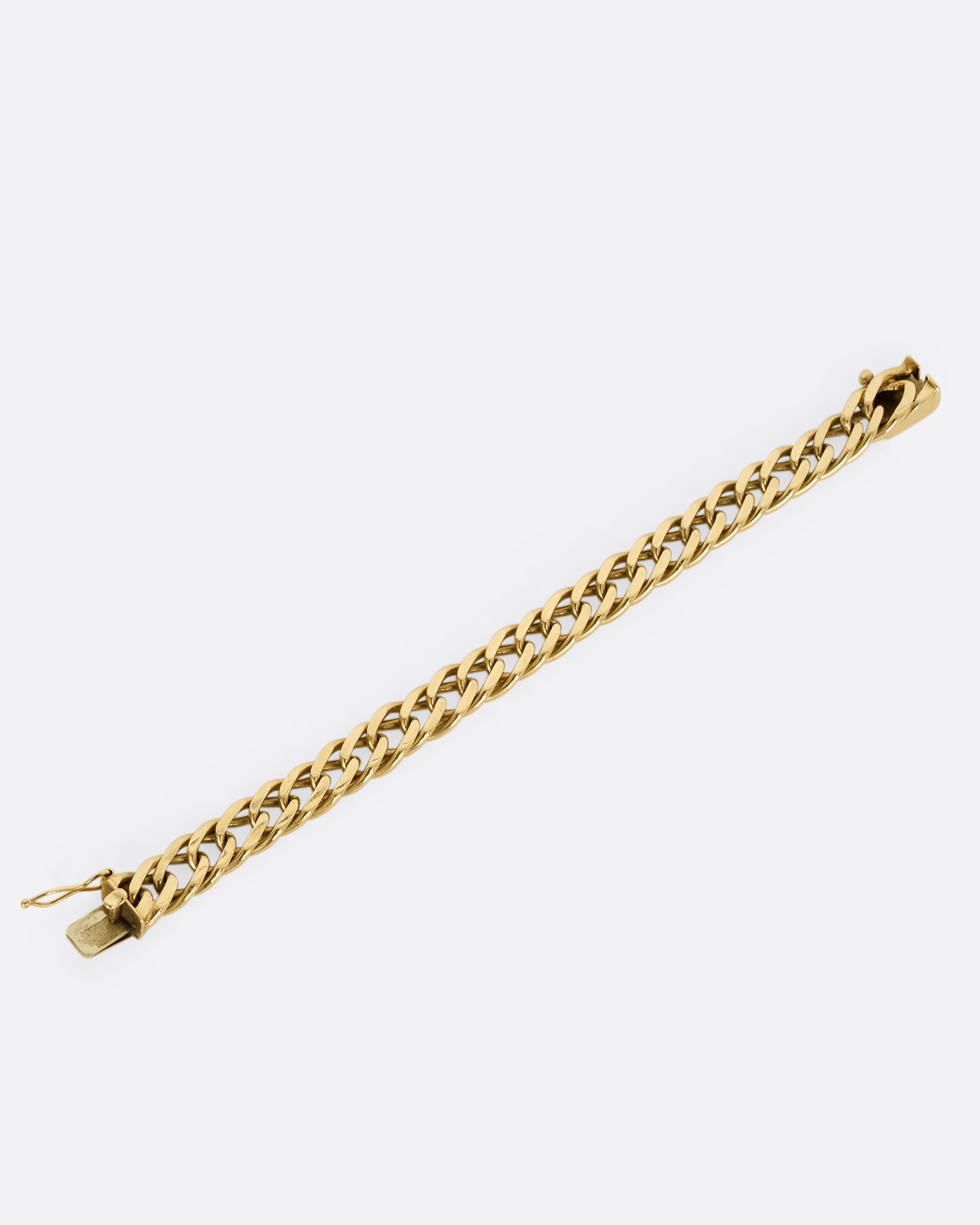 A yellow gold double curb chain bracelet. Shown laying flat.