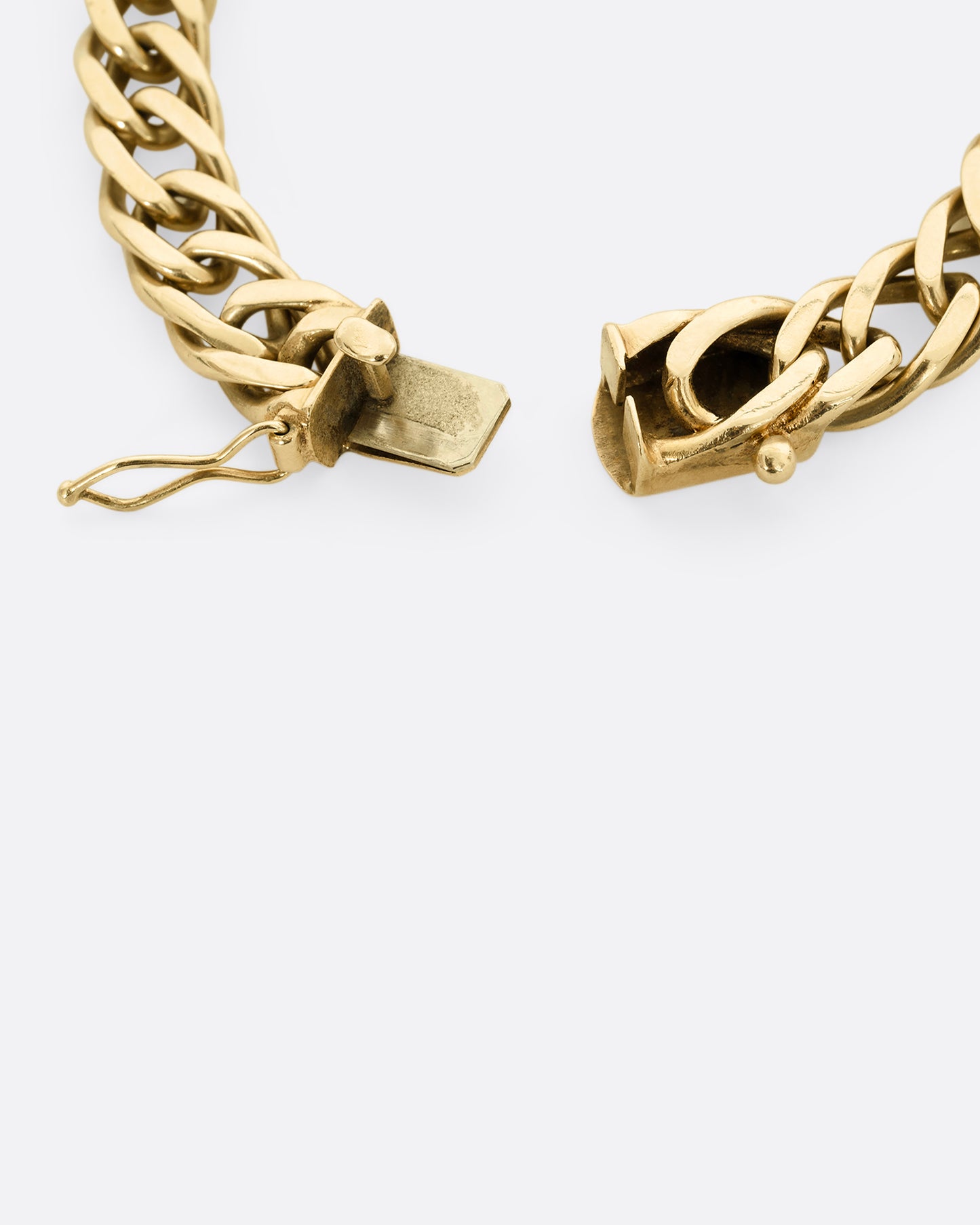 A yellow gold double curb chain bracelet. Close up of the clasp.