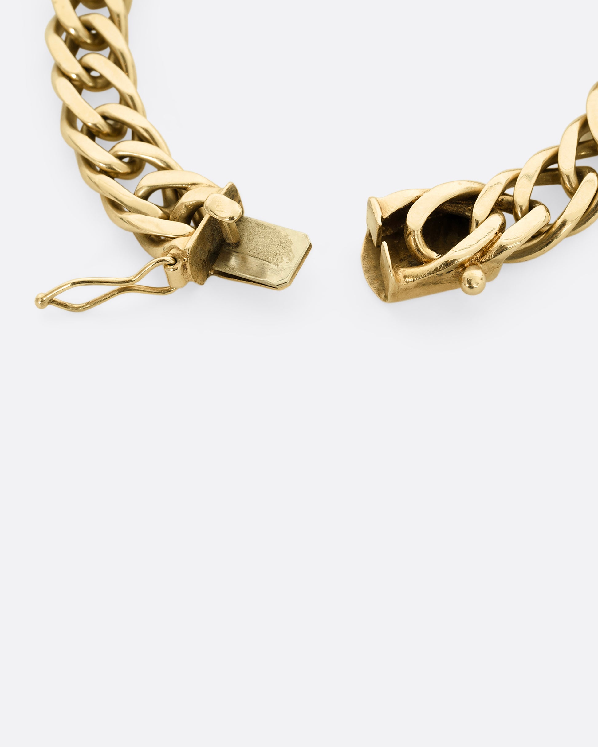 A yellow gold double curb chain bracelet. Close up of the clasp.