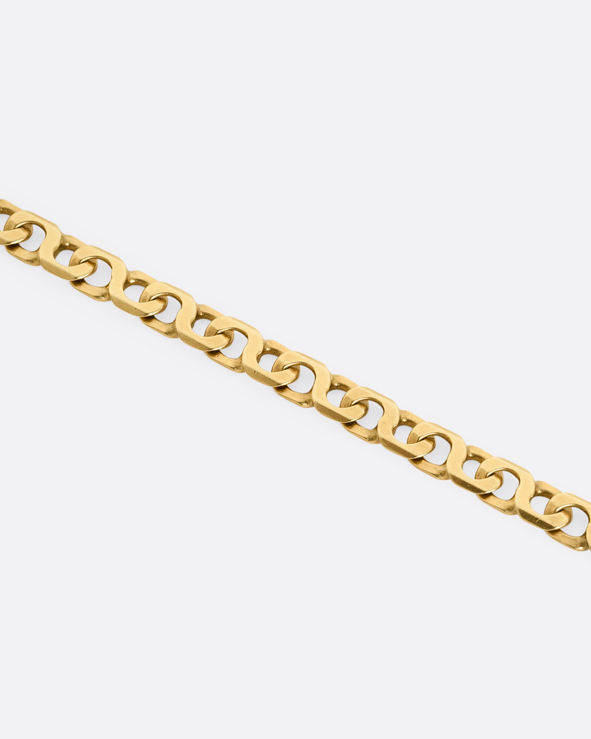 A yellow gold bracelet with infinity links Shown laying flat, close up.