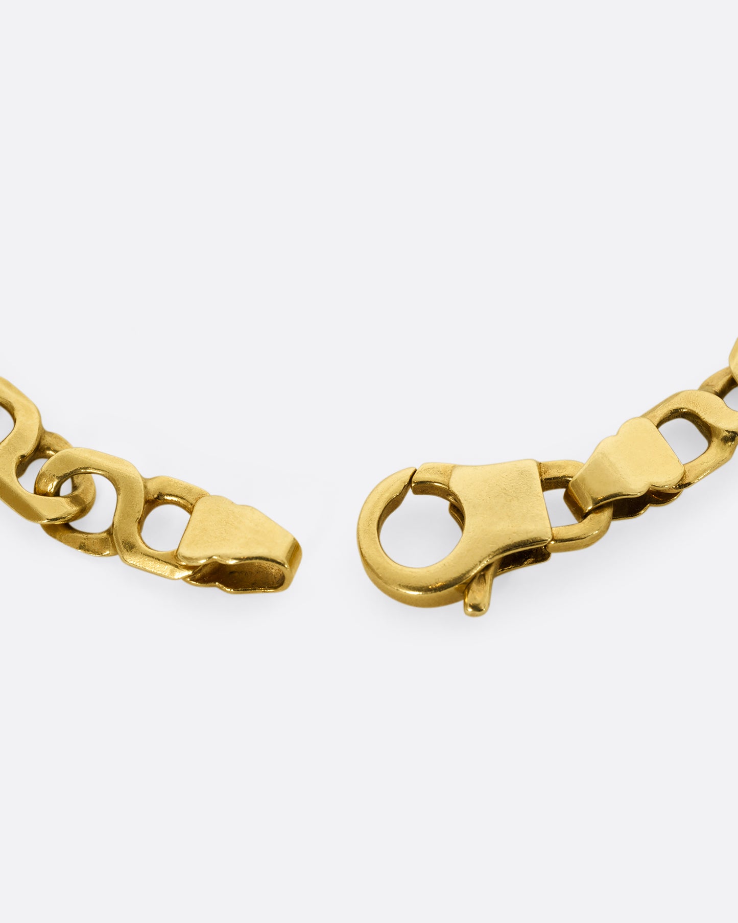 A yellow gold bracelet with infinity links Shown close up on the clasp.