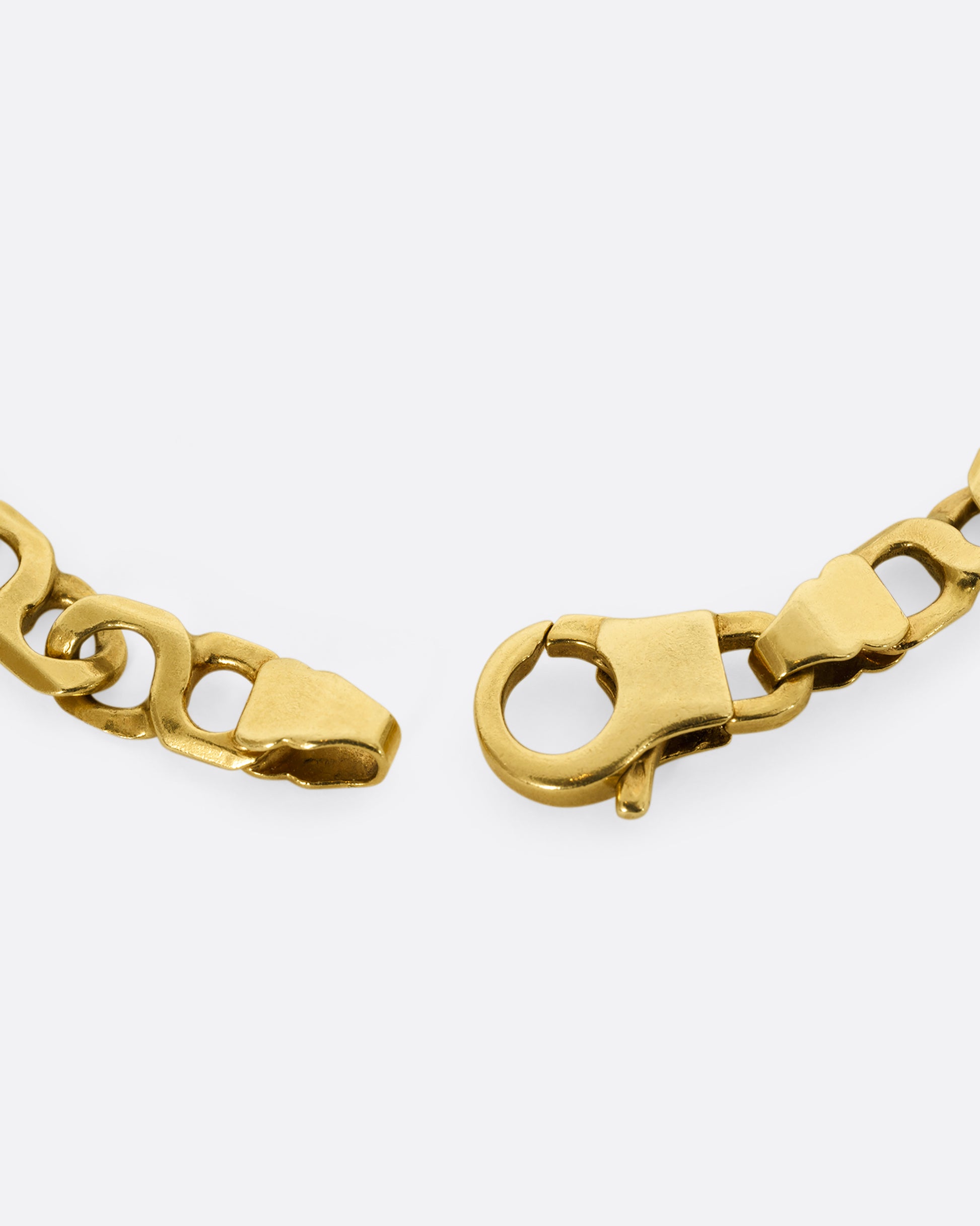 A yellow gold bracelet with infinity links Shown close up on the clasp.