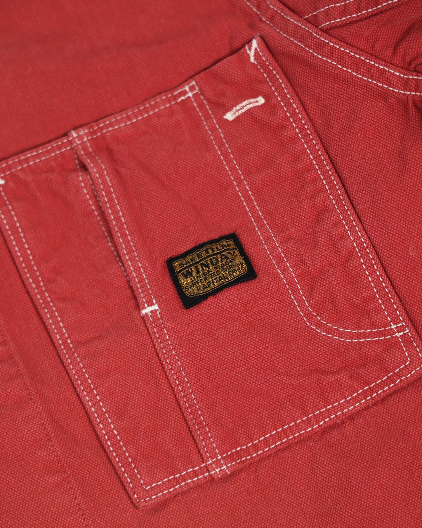 A red canvas chore coat with four front pockets. Close up of one of the pockets.