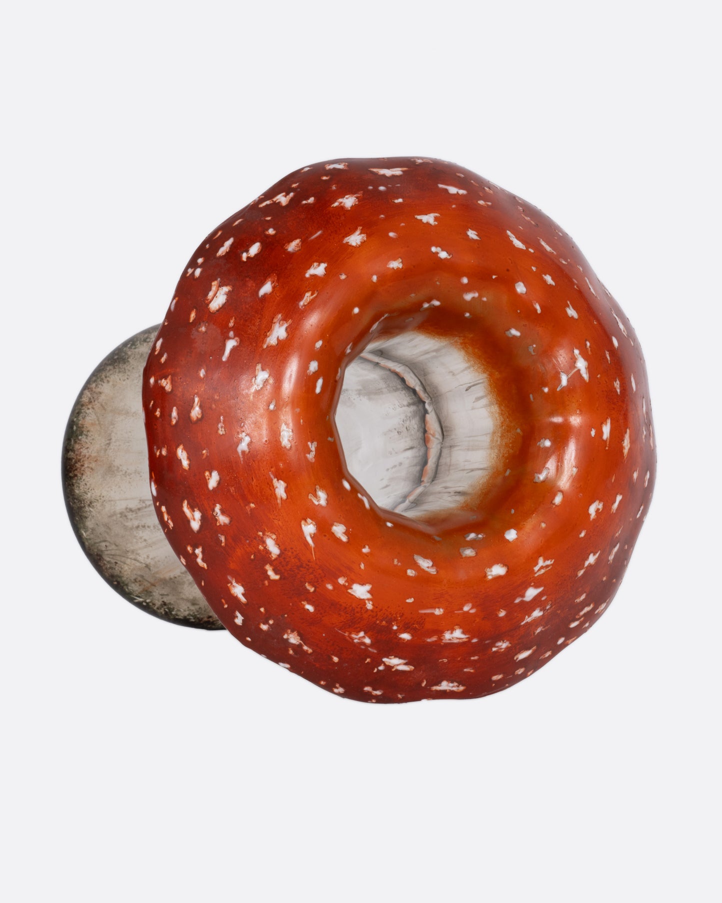 A hand painted red and white glass mushroom vase, shown from the top.