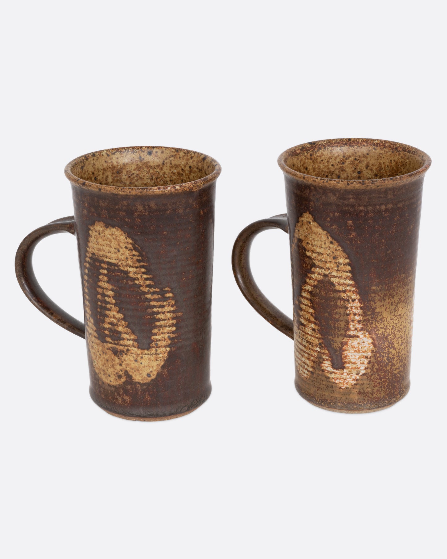 A pair of brown mugs with a ribbed texture and dynamic abstract glaze, shown from the side.