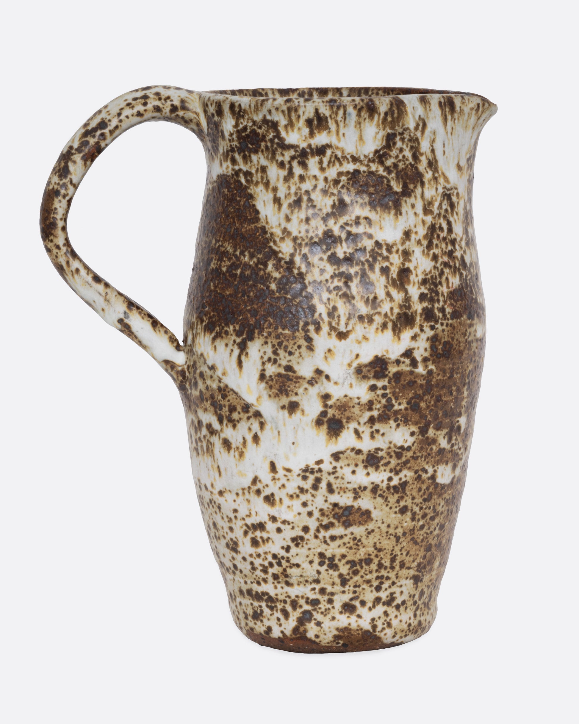 A speckled ceramic brown and cream pitcher, shown from the side.