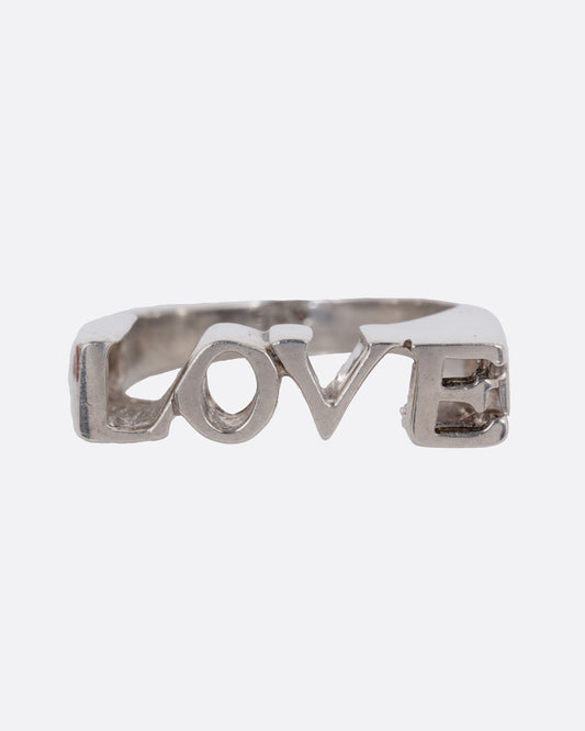 A silver ring with the letters LOVE, shown from the front.