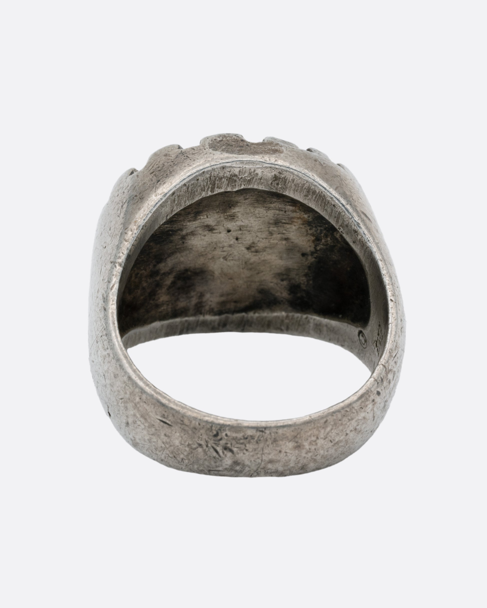 A silver ring with a graphic spiral sun, shown from the back.