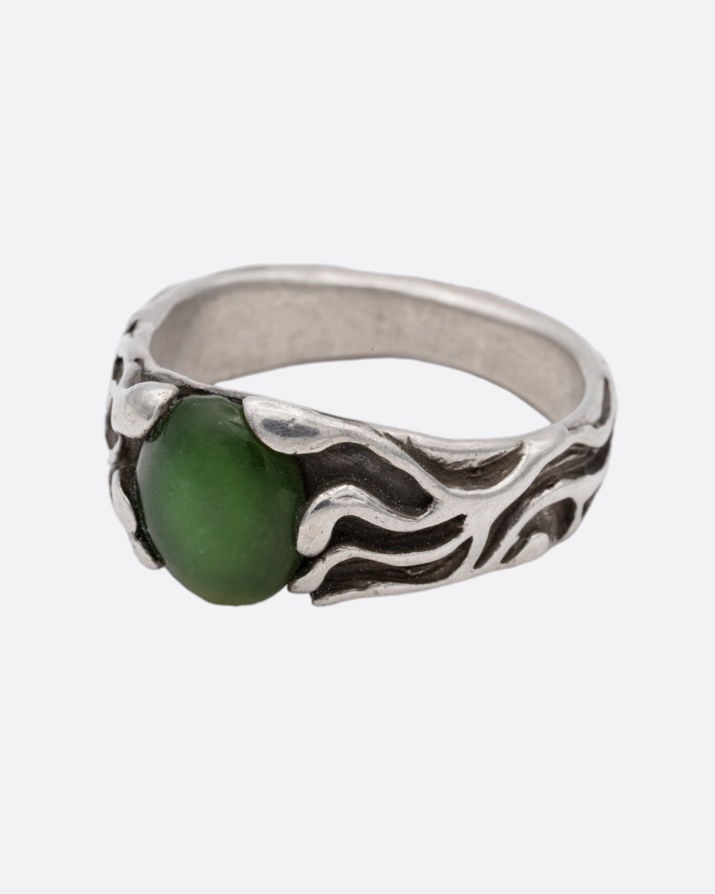 A silver ring with an oval jade at the center, shown from the side.