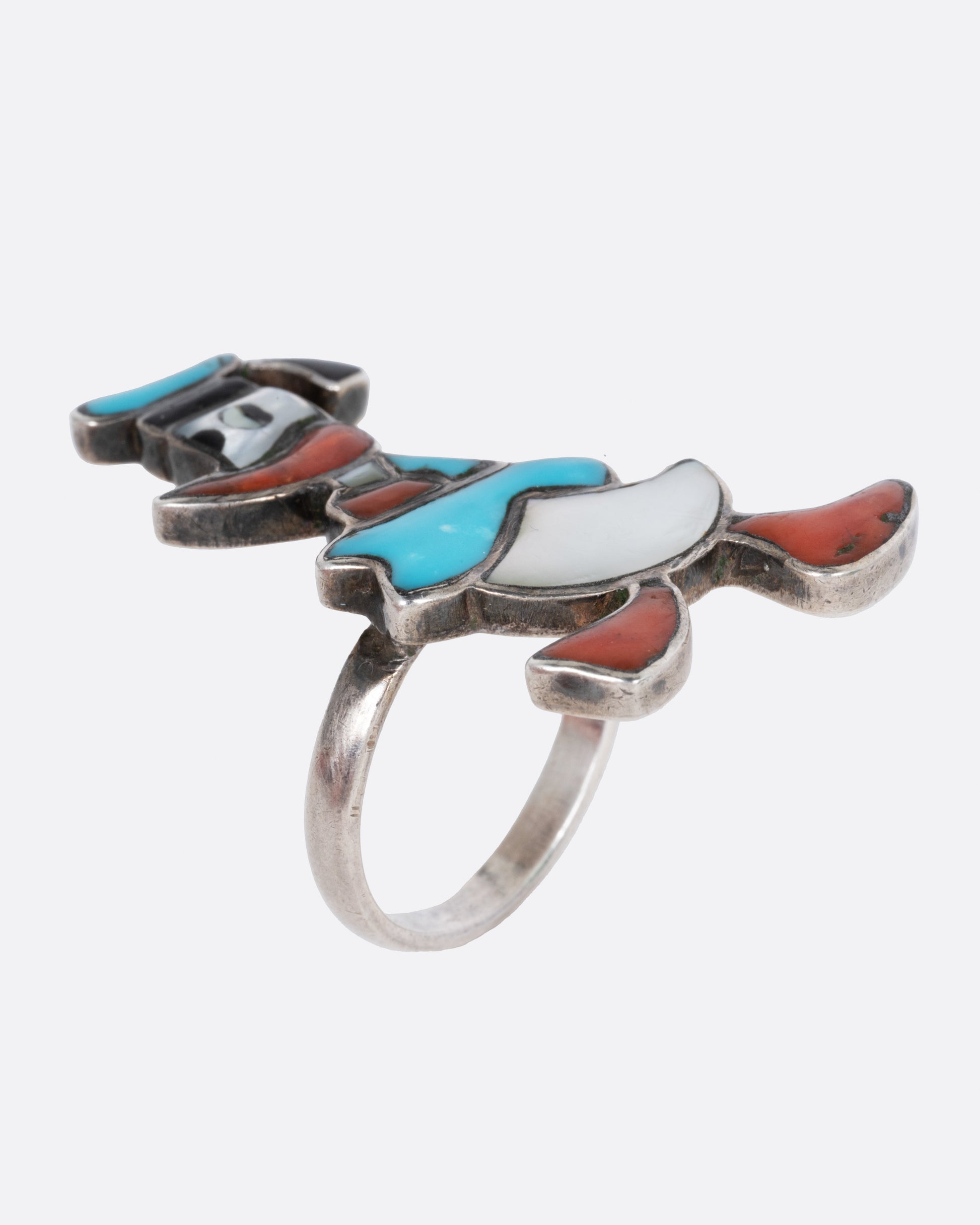 A Donald Duck ring with turquoise and mother-of-pearl inlay. Shown from the side standing up.