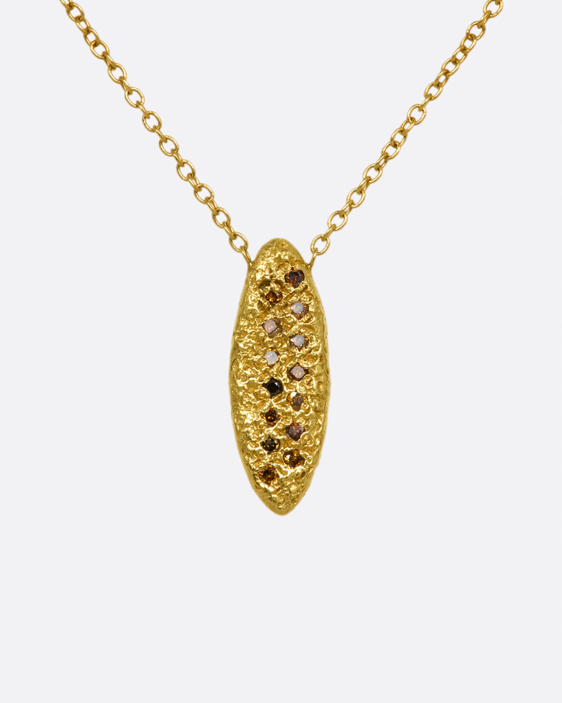 A yellow gold chain necklace with a marquise shape textured pendant, with two rows of red and brown diamonds.