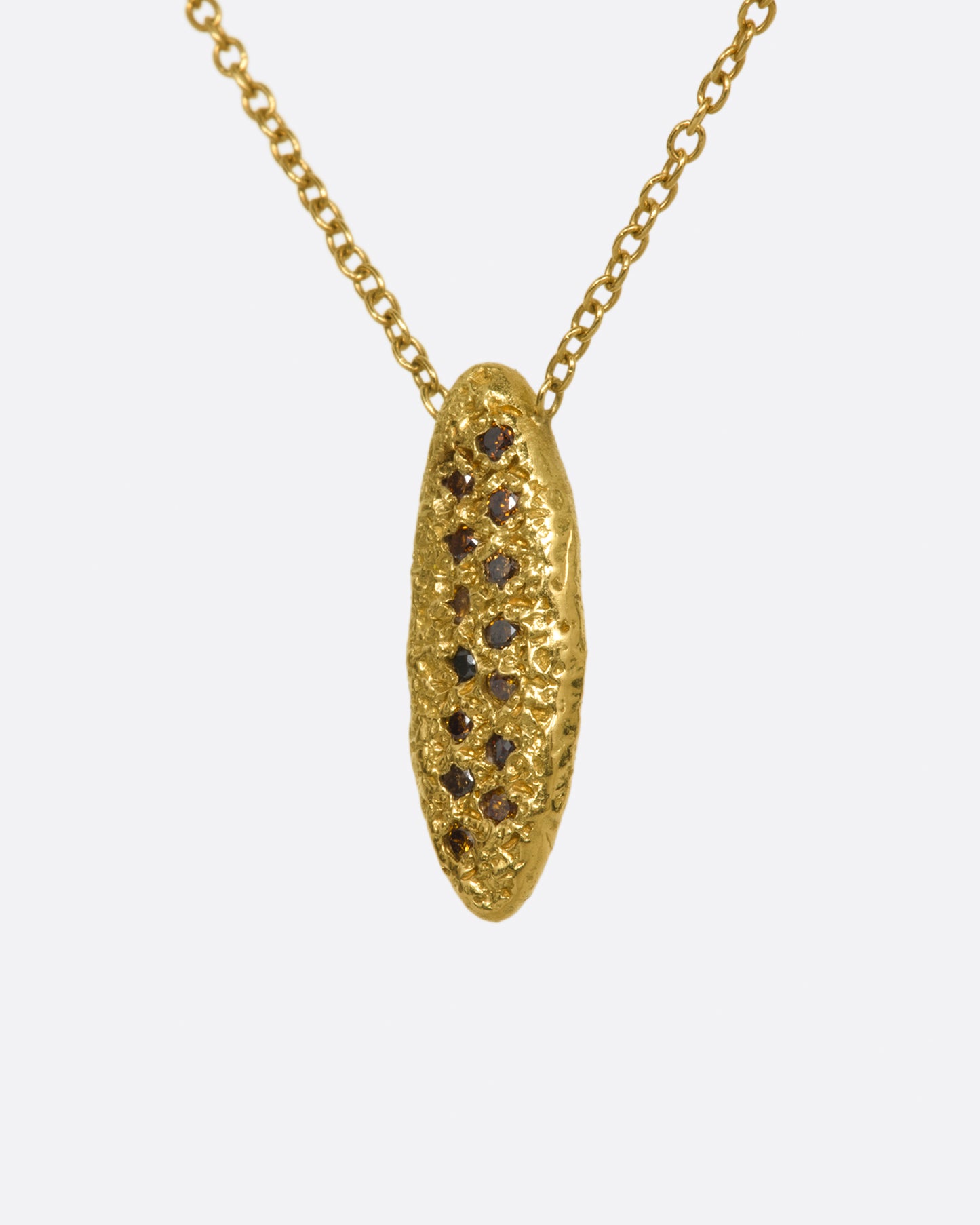 A yellow gold chain necklace with a marquise shape textured pendant, with two rows of red and brown diamonds. Shown from the side.