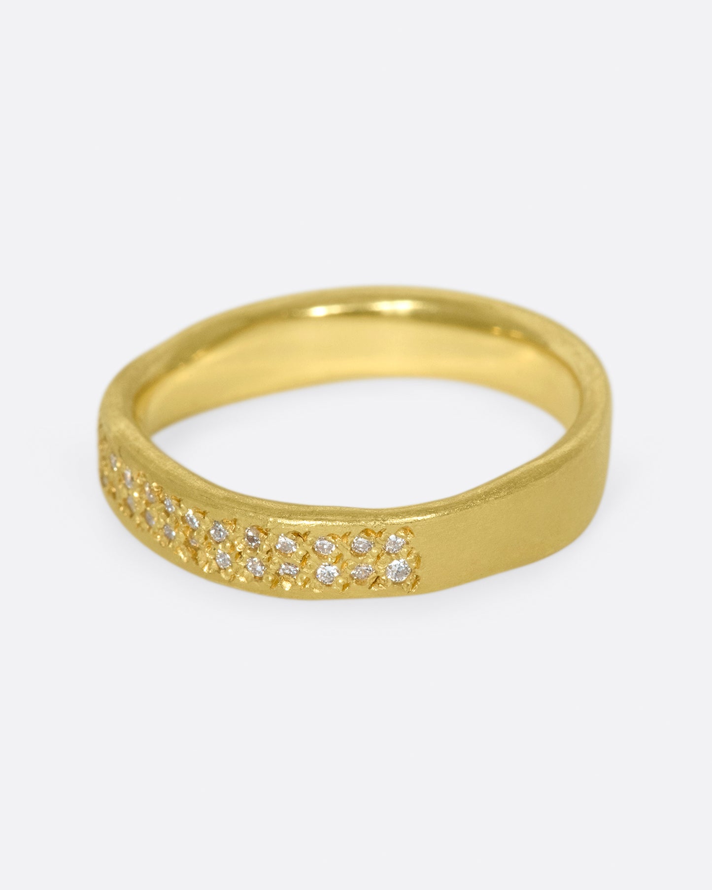 A hand-formed, brushed gold band with two rows of diamonds along half of it.