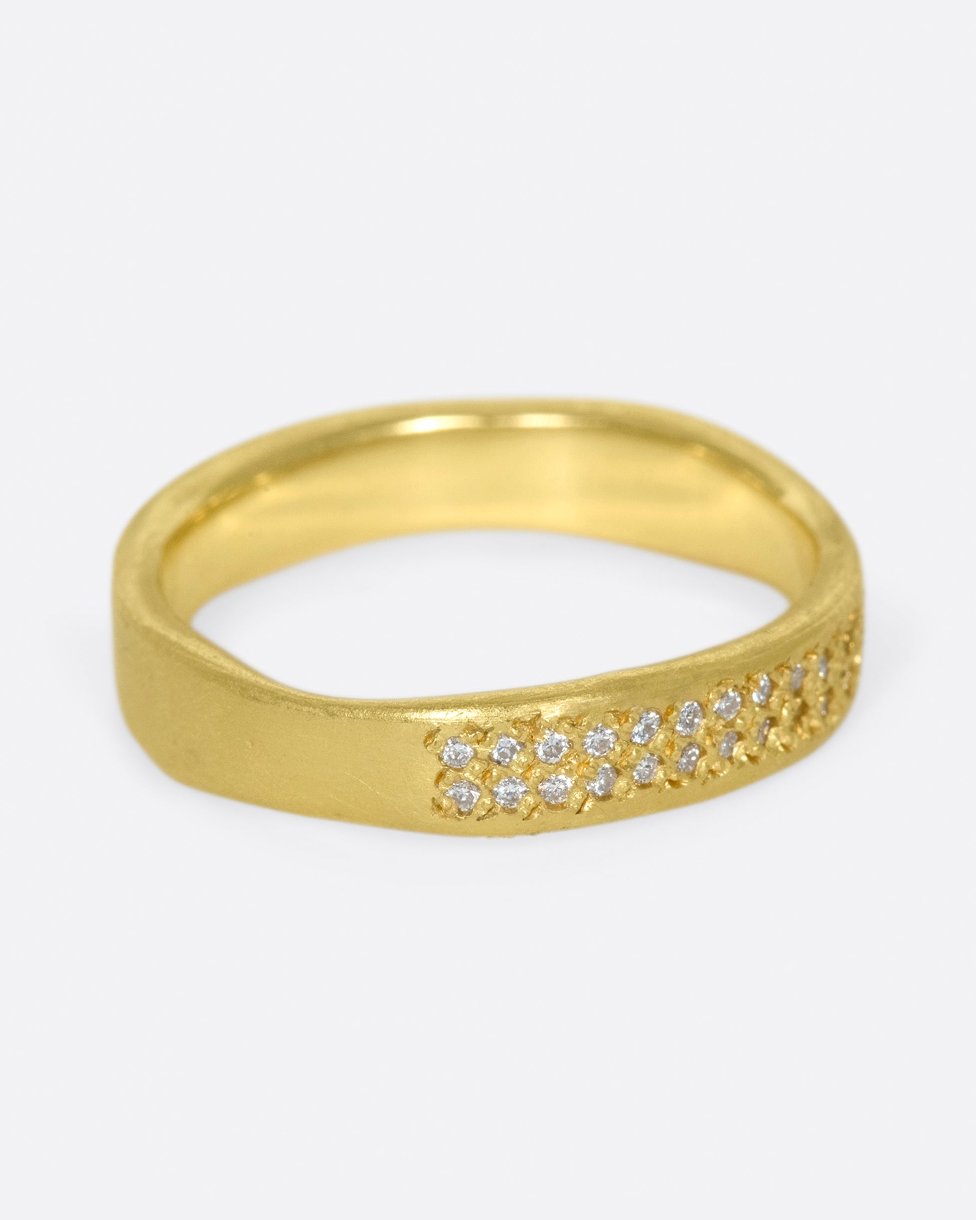 A hand-formed, brushed gold band with two rows of diamonds along half of it.