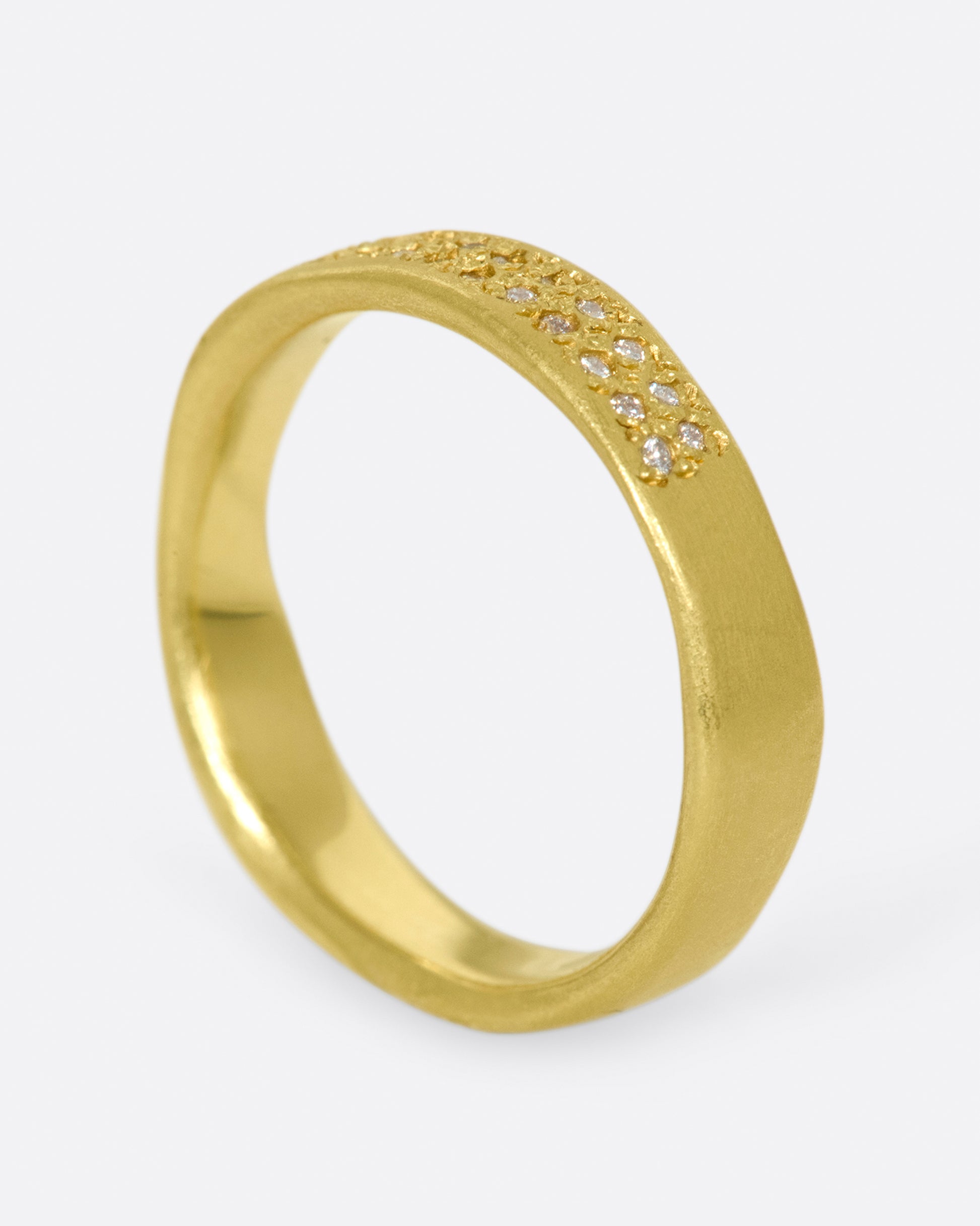 A hand-formed, brushed gold band with two rows of diamonds along half of it.